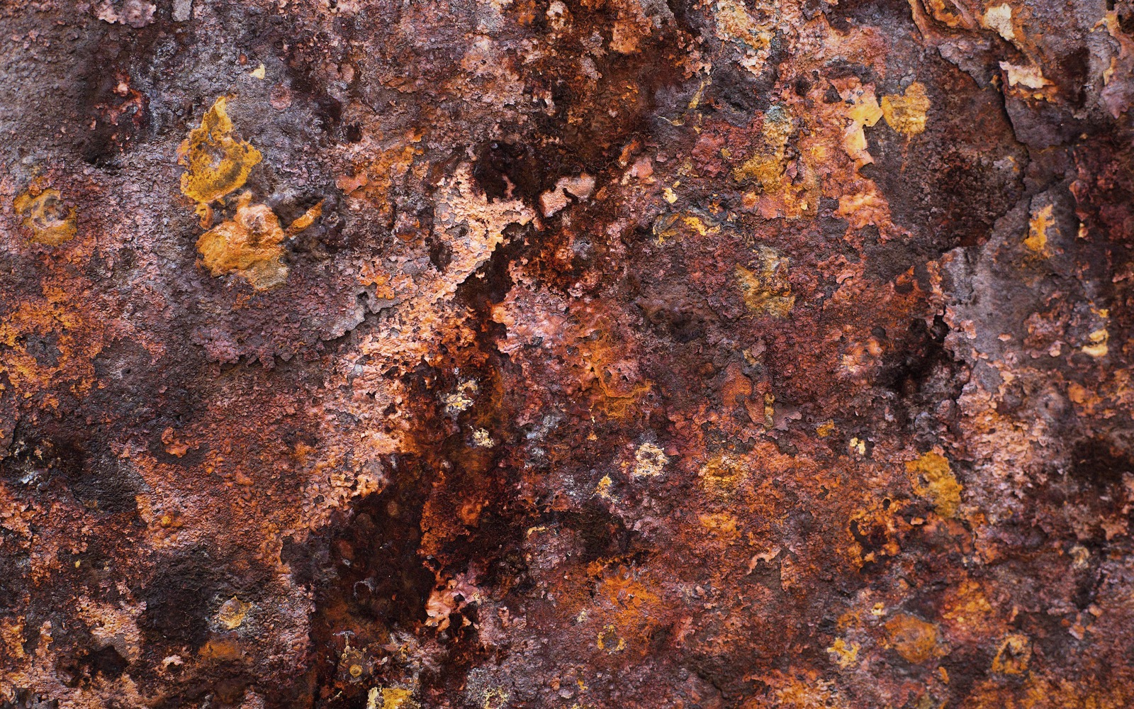 Close-up of heavily corroded steel surface with orange, brown and rust-colored patches